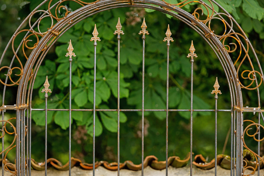 Rosenbogen Calabria mit Rückwand in Rostoptik Detailansicht frontal Rückwand mit Kreuzlilien-Spitzen Rosenbogen Calabria mit Rückwand in Rostoptik Detailansicht frontal Rückwand mit Kreuzlilien-Spitzen