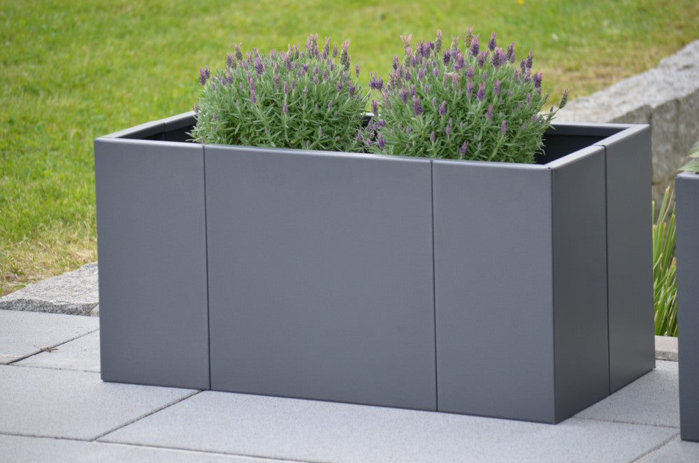 Pflanzkübel Vernazza 40x80x40 in Metall bepflanzt vor einem grünen Garten