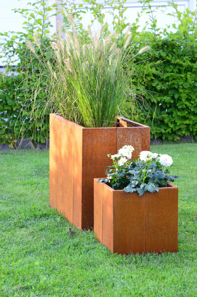 Pflanzkübel Vernazza 40x40x40 und Hohbeet in Cortenstahl in einem grünen Garten